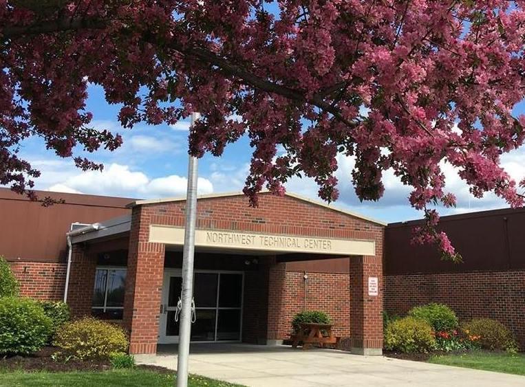 A front view shot of Northwest Technical Center with a pink blossom tree above it.