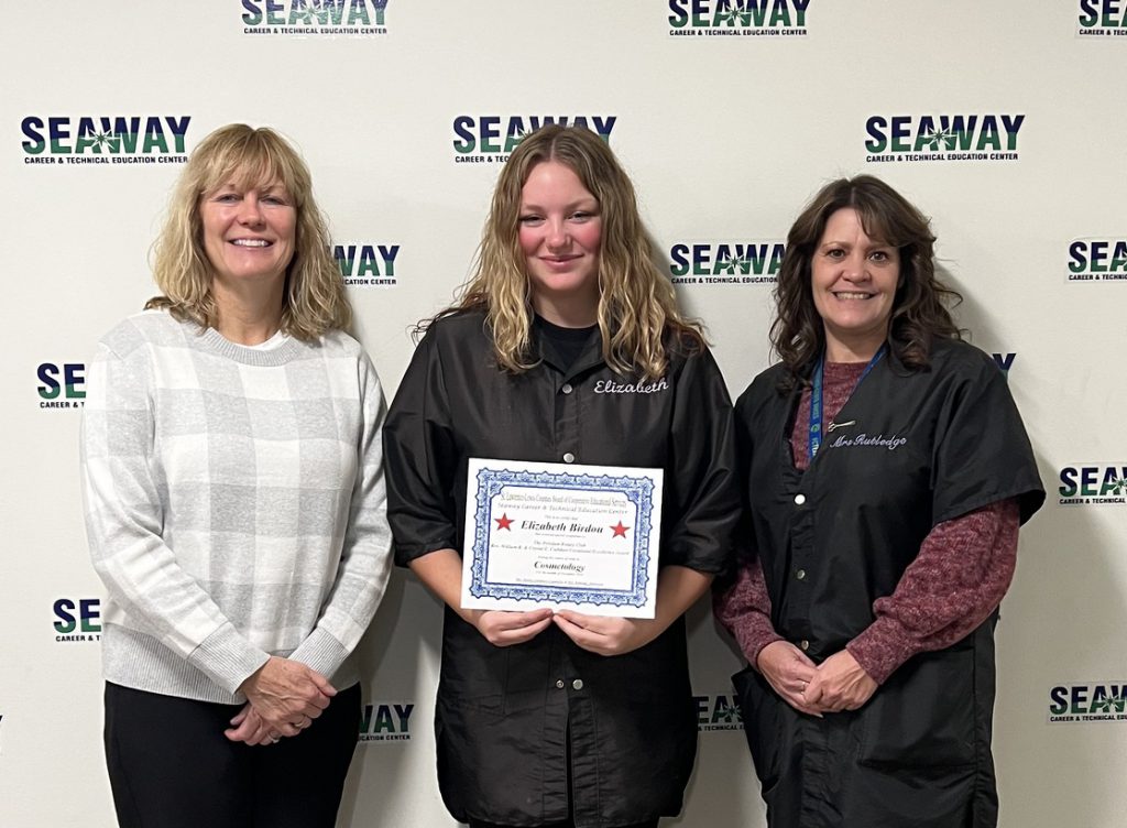 Elizabeth Birdou stands with an instructor and another adult as she holders her award certificate.