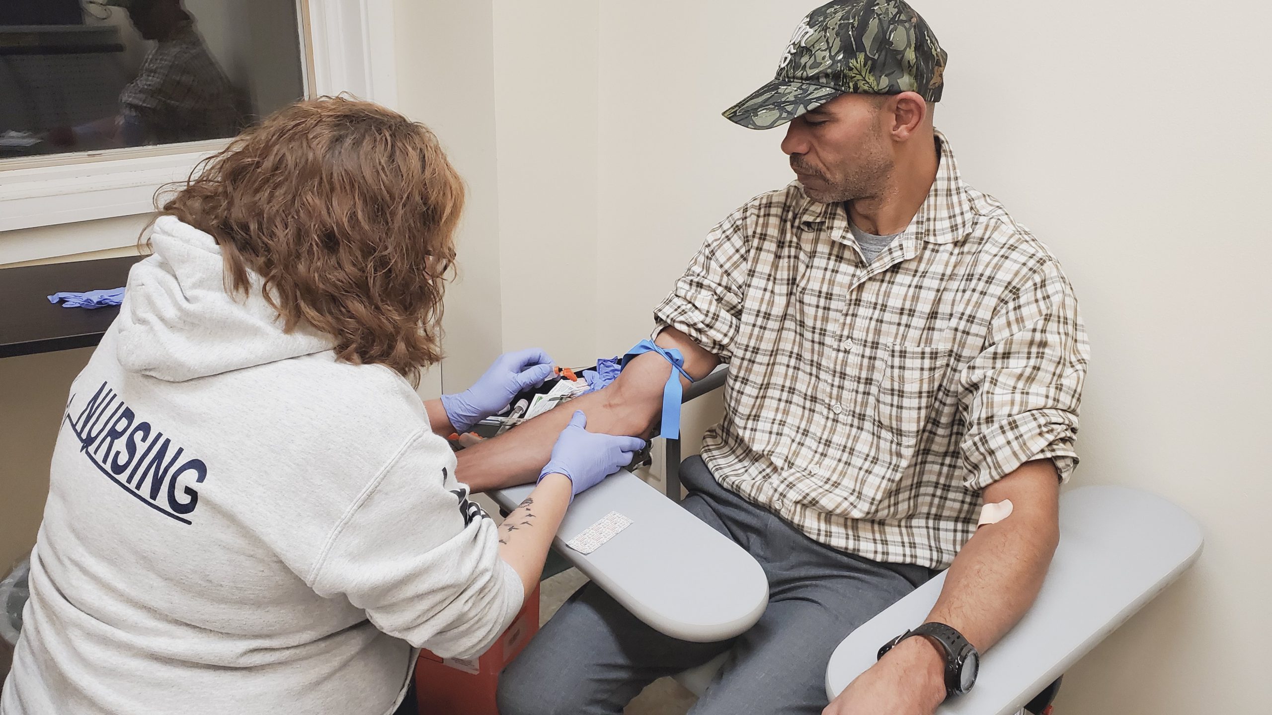 A phlebotomy student prepares to draw blood from a patient.