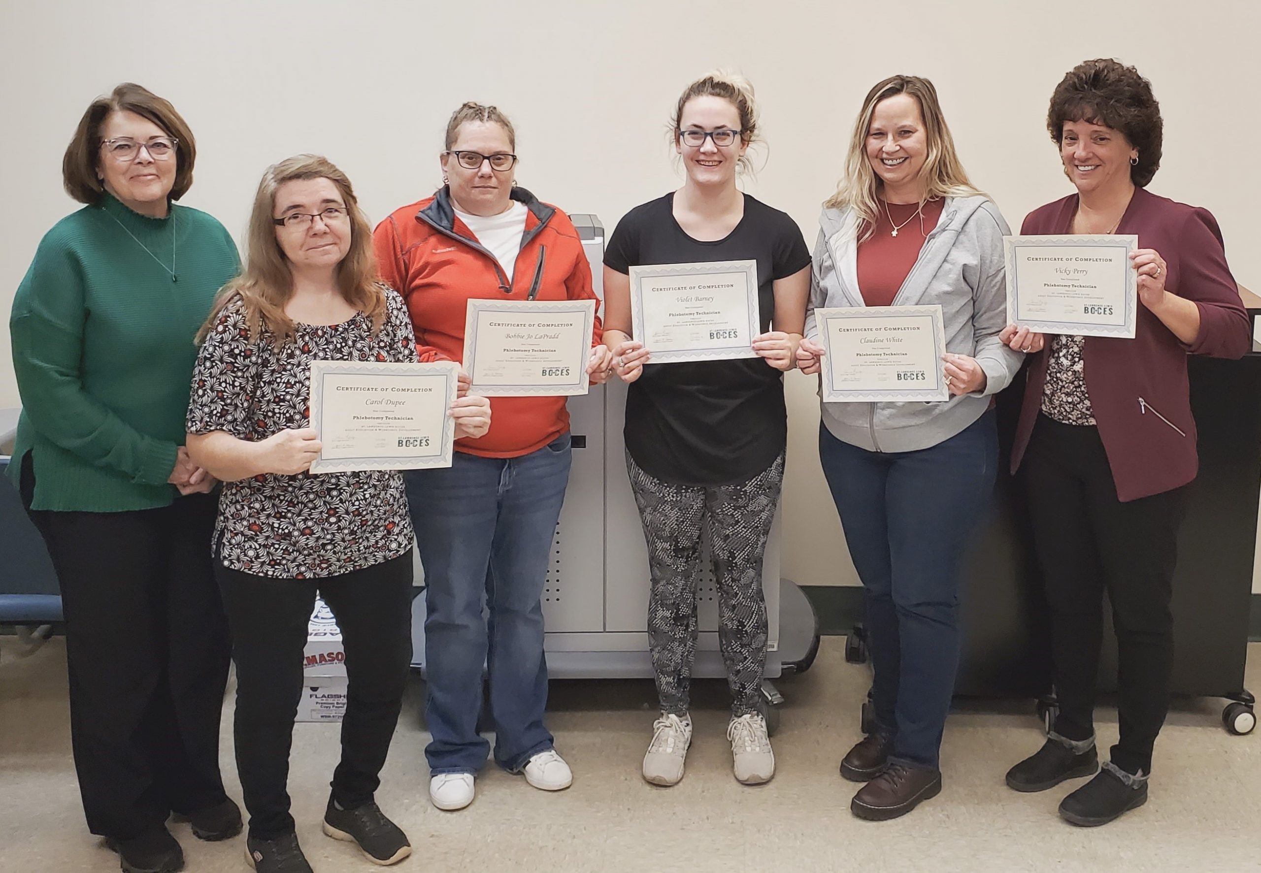 Phlebotomy students gathered together holding certificates.