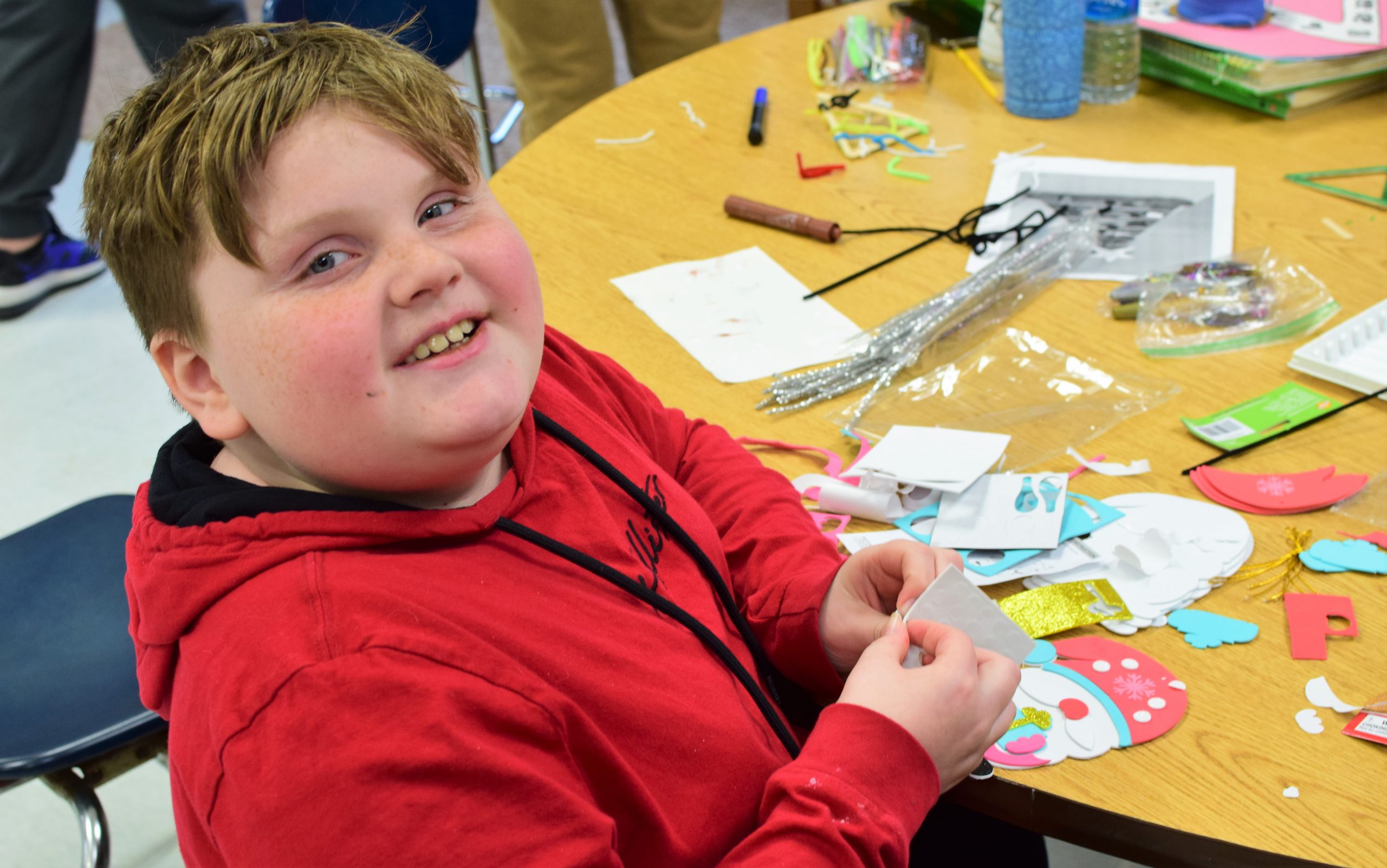 student working with paper at classroom, smiling directly at camera