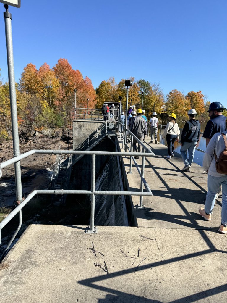 Students walk across the top of a dam at the Brookfield facility.